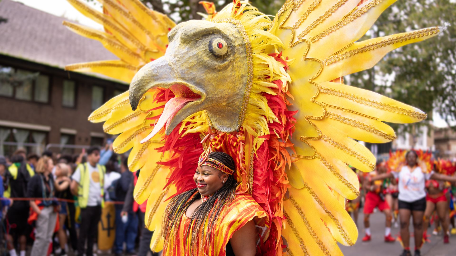 A carnival participant wears an oversized golden bird costume during the Notting Hill Carnival parade.