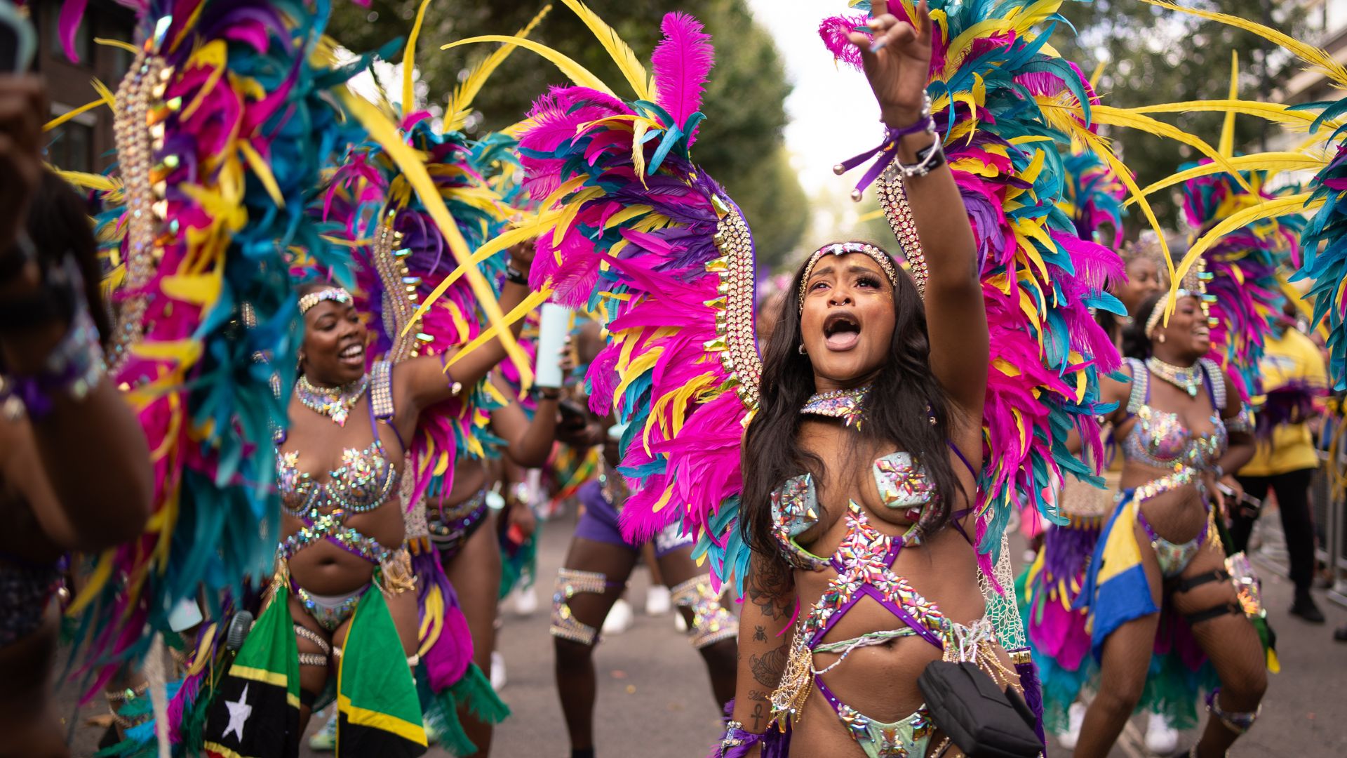 Carnival dancers wearing colourful feathered costumes perform in the Notting Hill Carnival parade.