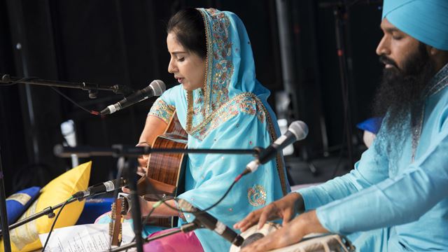 Two people playing instuments on stage, dressed in light blue clothing.