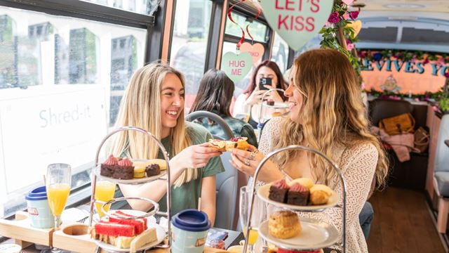 Two people cheers drinks aboard a valentines themed afternoon tea bus tour