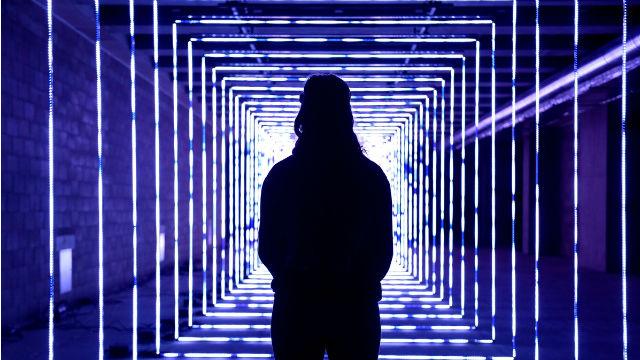 Un homme de dos marche à travel un tunnel illuminé de lumières bleues à Canary Wharf.