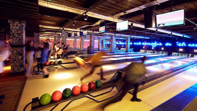 Blurred people bowling on the lanes at Queens in London.