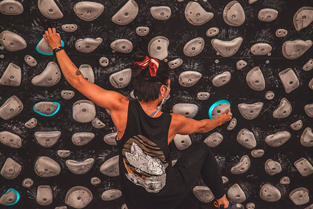 A woman climbing a grey bouldering wall at Stronghold Climbing Centre.