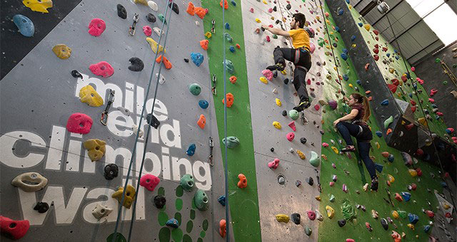 Get to grips with the Mile End Climbing Wall © Andy Day. Image courtesy of Andy Day / Mile End Climbing Wall. A man and woman climbing Mile End Climbing wall with ropes