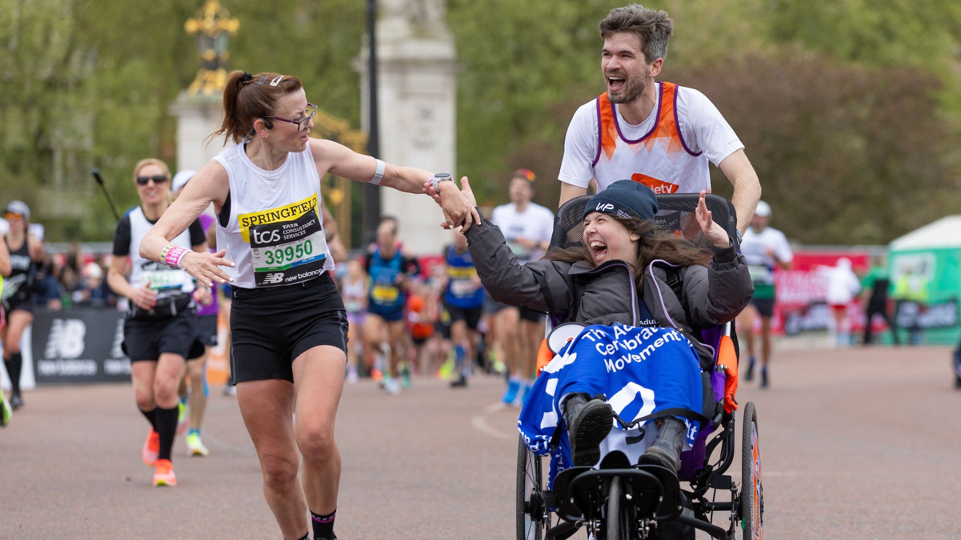 Rosie Jones and Evo Graham high five a participant a they make their way past Buckingham Palace during The TCS London Marathon on Sunday 21st April 2024.