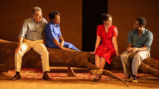 Two men and two women sit on a large tree branch in a scene from the play All My Sons, starring Bryan Cranston, Marianne Jean-Baptiste and Paapa Essiedu.