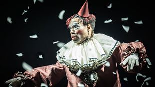 Billy Porter joue le rôle du maître de cérémonie dans la comédie musicale Cabaret au Kit Kat Club, vêtu d'un costume de clown rouge et entouré de confettis blancs.