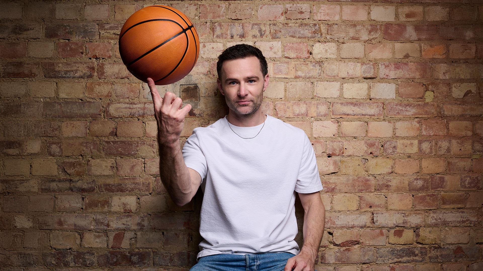 In a promotional shot of his casting as Coach Bolton in High School Musical, Harry Judd is pictured sitting with a basketball rolling on his finger.