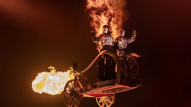 Two actors suspended on a chariot on fire as part of a theatre production of The Hunger Games.