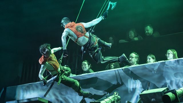 Two male actors fighting as tributes for survival while suspended in the air during a performance of The Hunger Games: On Stage in London.