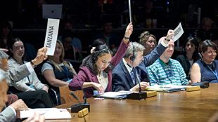 The actors who play the ambassadors in the Kyoto play are holding signs with names of the countries on them.