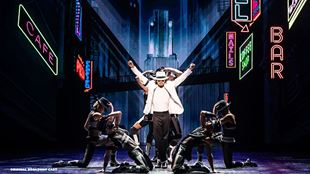 Myles Frost in the role of Michael Jackson is dancing on stage while wearing a black and white suit and the iconic hat.