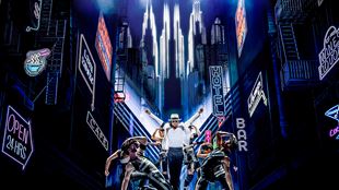 Myles Frost, dans le rôle de Michael Jackson, danse sur scène en portant un costume noir et blanc et le chapeau emblématique.