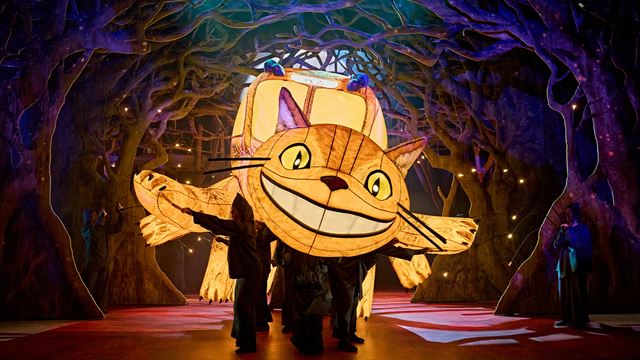 The giant inflatable yellow Cat Bus flies onto the stage, leaving a forested landscape behind it.