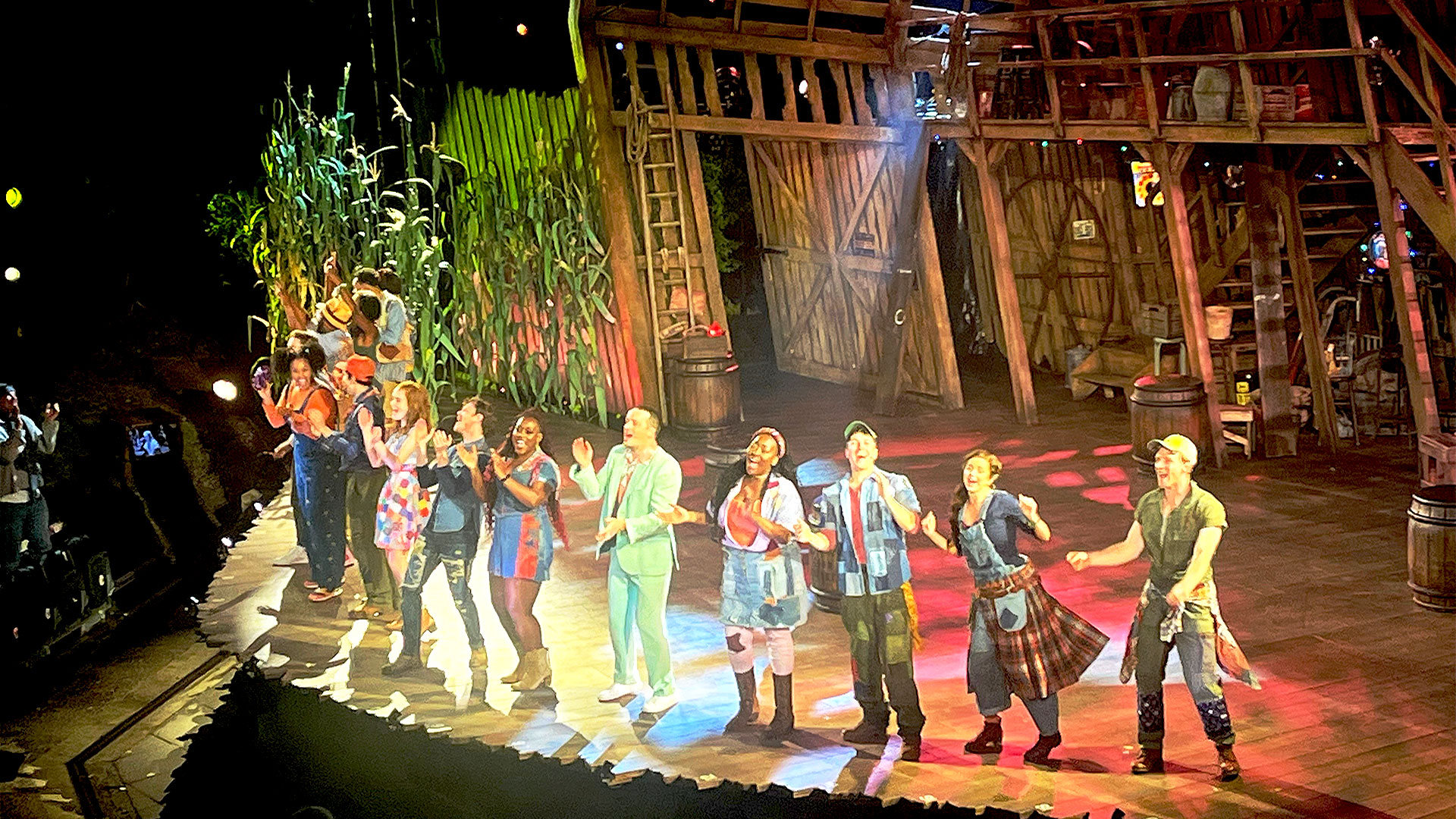 The cast of Shucked the Musical cheers and dances on stage, applauded by the public at the Regent's Park Open Air Theatre.