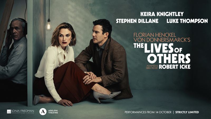 The Lives of Others starts Keira Knightley, Stephen Dillane and Luke Thompson in a new stage adaptation by Robert Icke. Image courtesy of London Theatre Direct. Promotional artwork for The Lives of Others showing three characters in a tense, dimly lit interior. A man wearing headphones listens from behind a partition while a woman and a man sit closely together in the foreground. The title and cast names appear alongside the image.