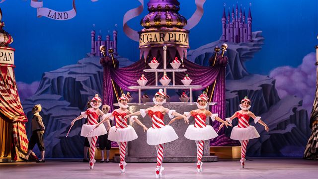 During the production of The Nutcracker Ballet at the London Coliseum, five ballet dancers wearing red and white striped tights and bodices are dancing on stage.