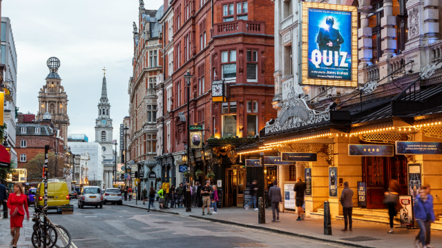 Outside of theatre with billboard and view of street in the West End.