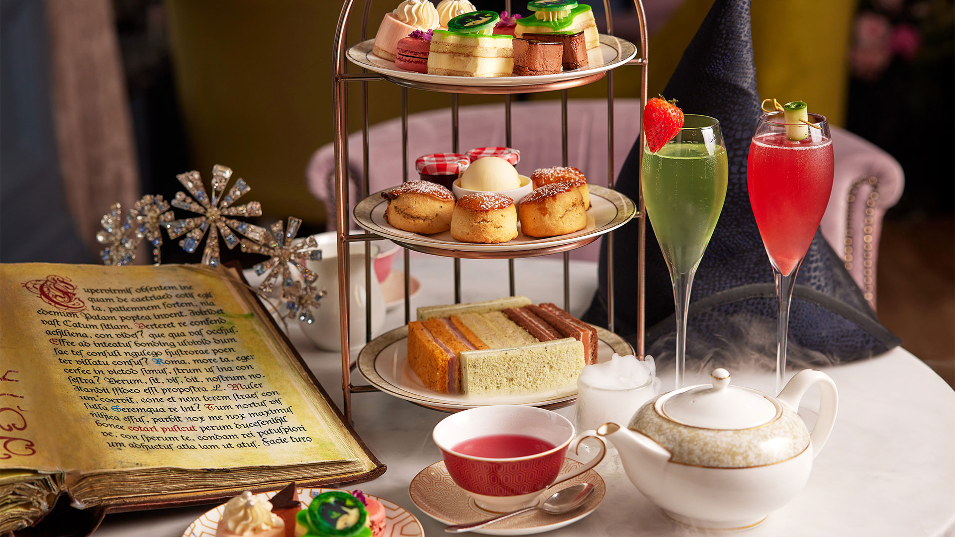 Dive into the world of Wicked with a spectacular and delicious themed afternoon tea at the Clermont Hotel in Victoria. Image courtesy of the Clermont Hotel Victoria. A three-tier tray bearing various sandwiches, scones and individual cakes is presented alongside two cocktails, a black witch hat and what looks like a grimoire as part of the Wicked Afternoon Tea at the Clermont Hotel in Victoria.