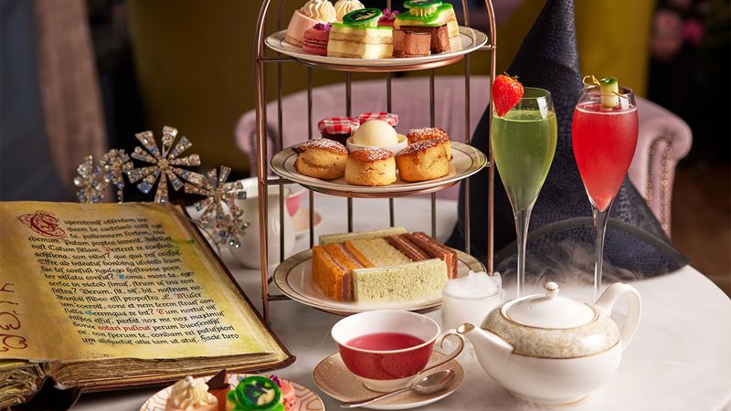 Dive into the world of Wicked with a spectacular and delicious themed afternoon tea at the Clermont Hotel in Victoria. Image courtesy of the Clermont Hotel Victoria. A three-tier tray bearing various sandwiches, scones and individual cakes is presented alongside two cocktails, a black witch hat and what looks like a grimoire as part of the Wicked Afternoon Tea at the Clermont Hotel in Victoria.