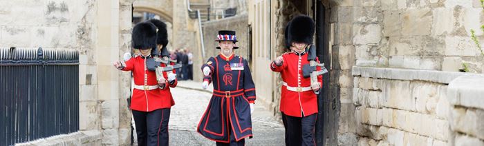 Des gardes Yeoman habillés de leurs uniformes rouge et noir marchent à travers la Tour de Londres.