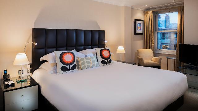 Double bedroom featuring a double bed with white sheets and colourful cushions.