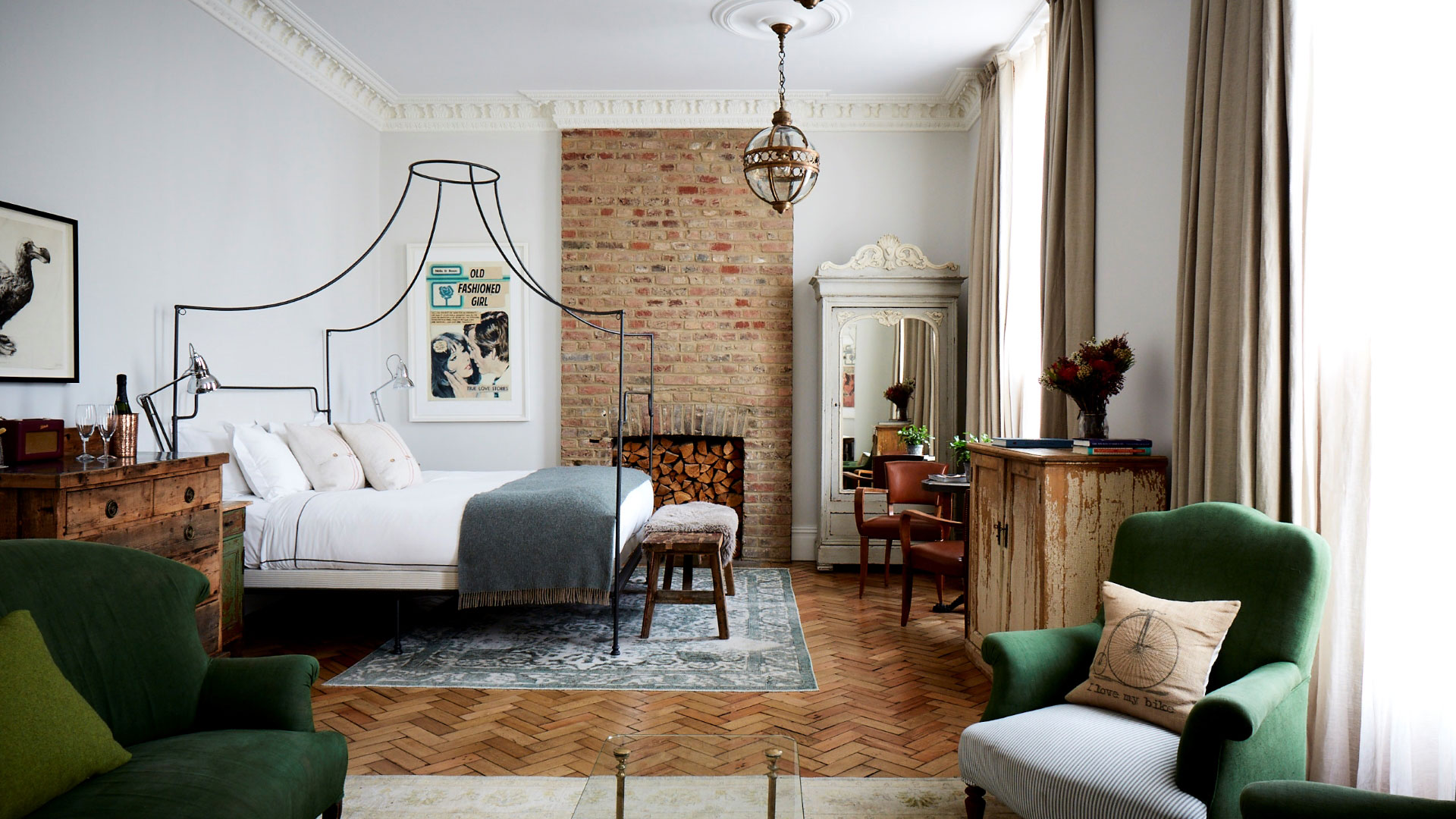 Room inside the Artist Residence with a four-poster bed, wooden parquet flooring and homely furniture
