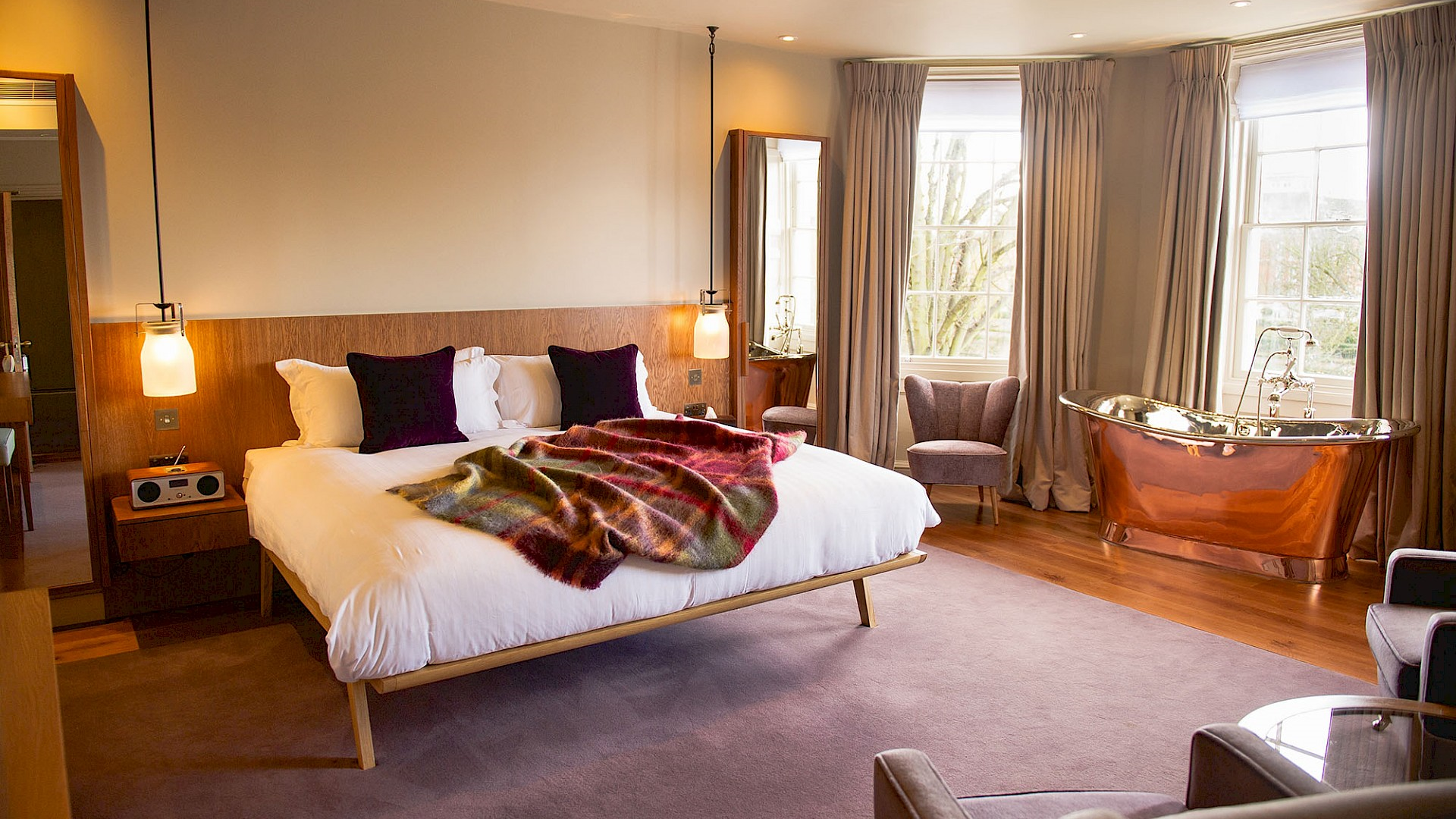 Cosy room at Bingham Riverhouse with a double bed, gold freestanding bath tub and large windows looking out onto the garden