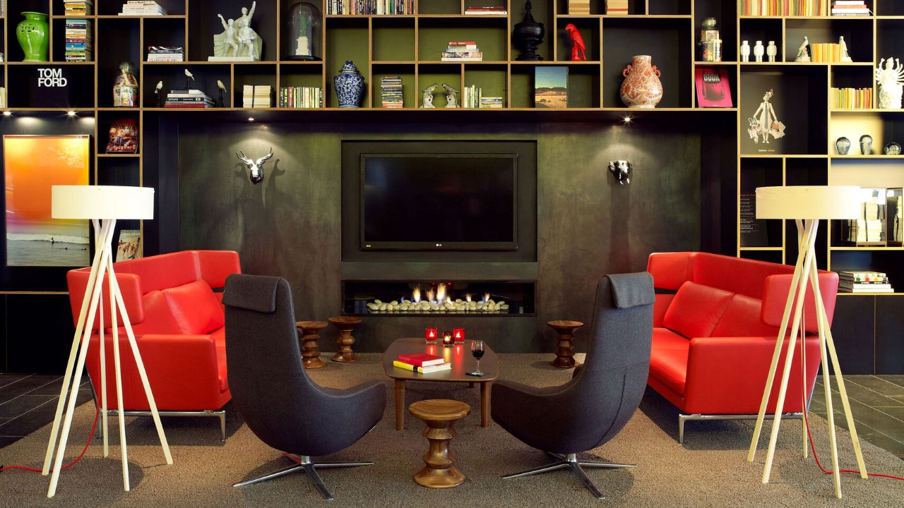 Sofas and chairs form a round in the modern lounge with a television, fireplace and bookcase