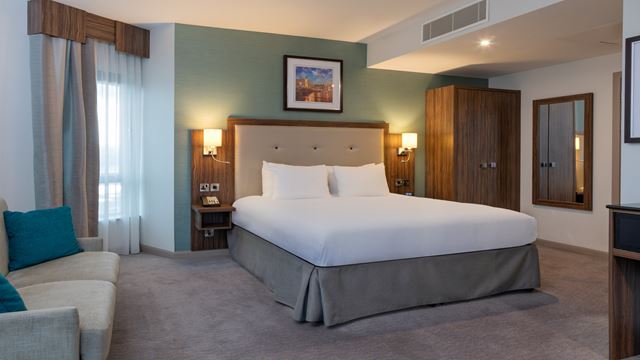 Hotel bedroom with king sized bed and sofa large window