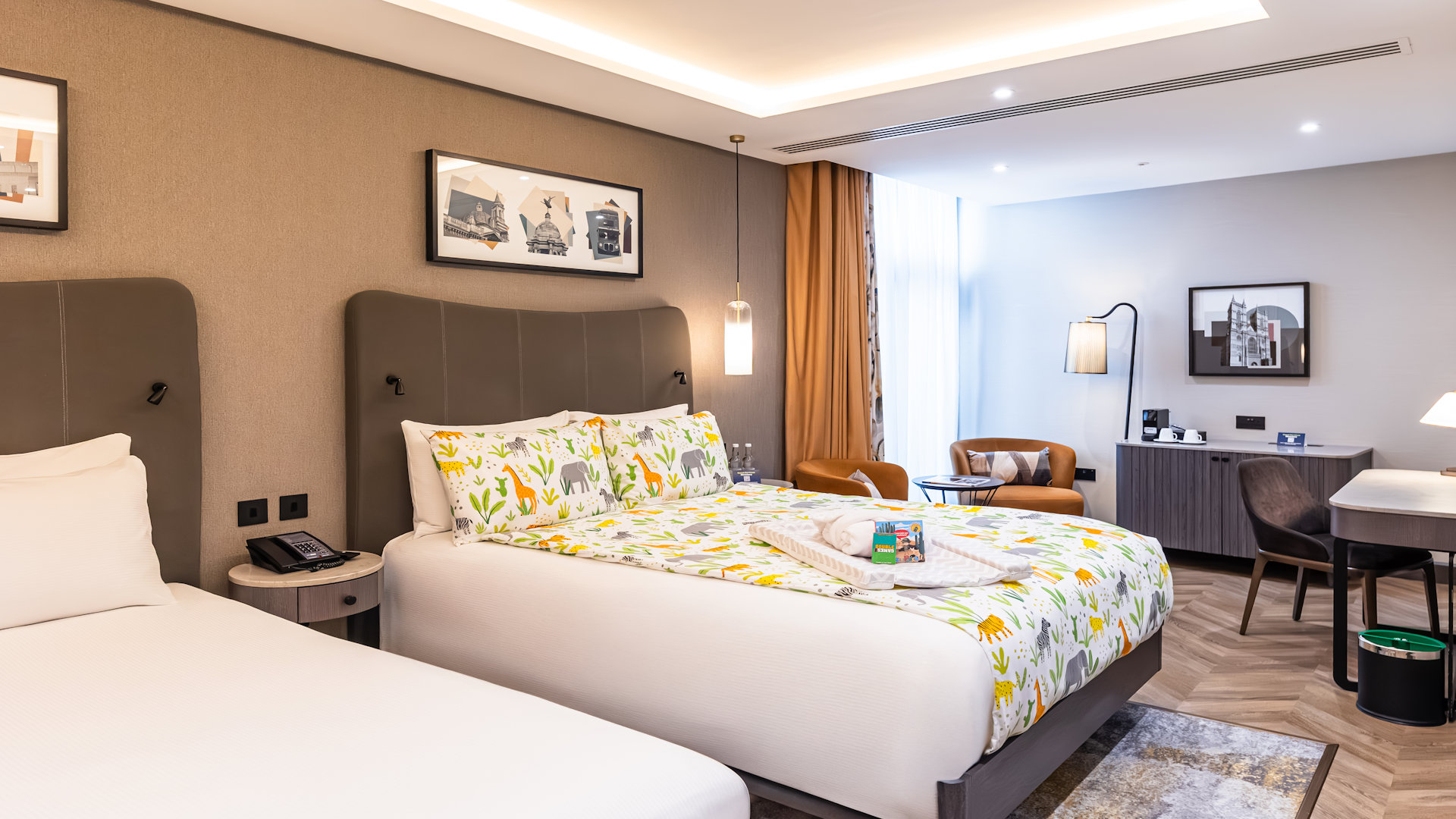 Hotel bedroom with two beds. Childs bedding, changing mat, bath robe and books on the bed