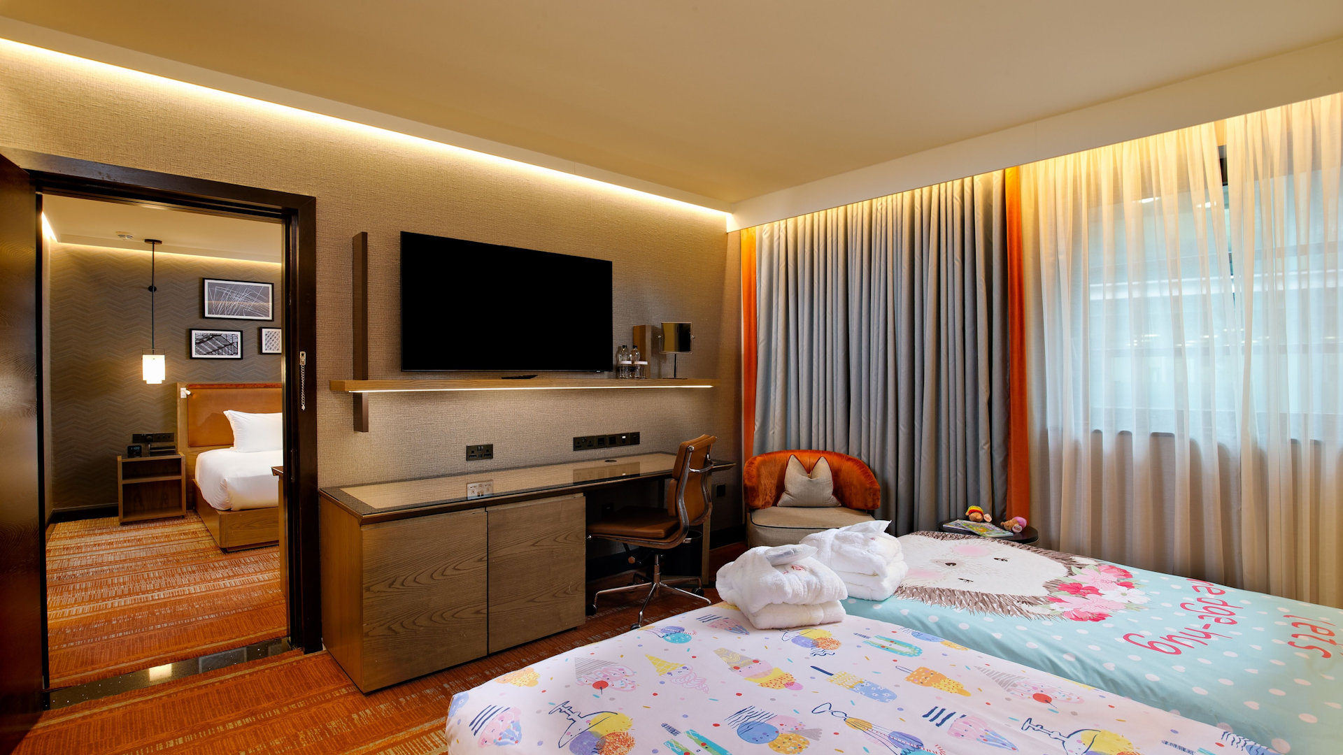 Family hotel bedroom, with two beds and children's bedding, television on the wall and chest of drawers