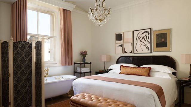 An elegant bedroom featuring a bath and large window