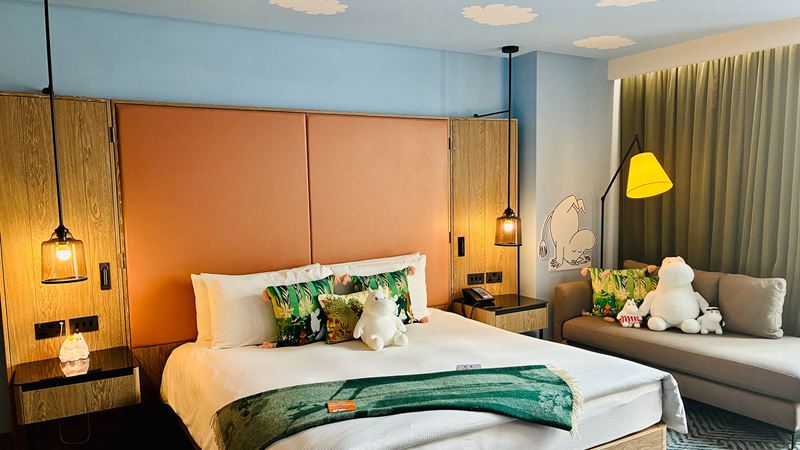 A double bed in a Moomin-themed room featuring Moomin toys
