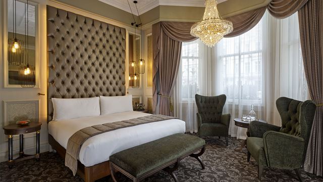 Bedroom with plush details and chandelier at 100 Queen's Gate Hotel London.