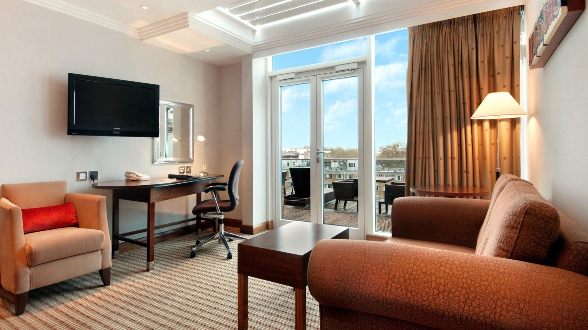 Détendez-vous dans la suite familiale avec terrace extérieure du Hilton London Paddington. Image gracieusement fournie par Hilton. Salon de la Suite Terrasse Familiale avec vue sur le balcon extérieur au Hilton London Paddington.