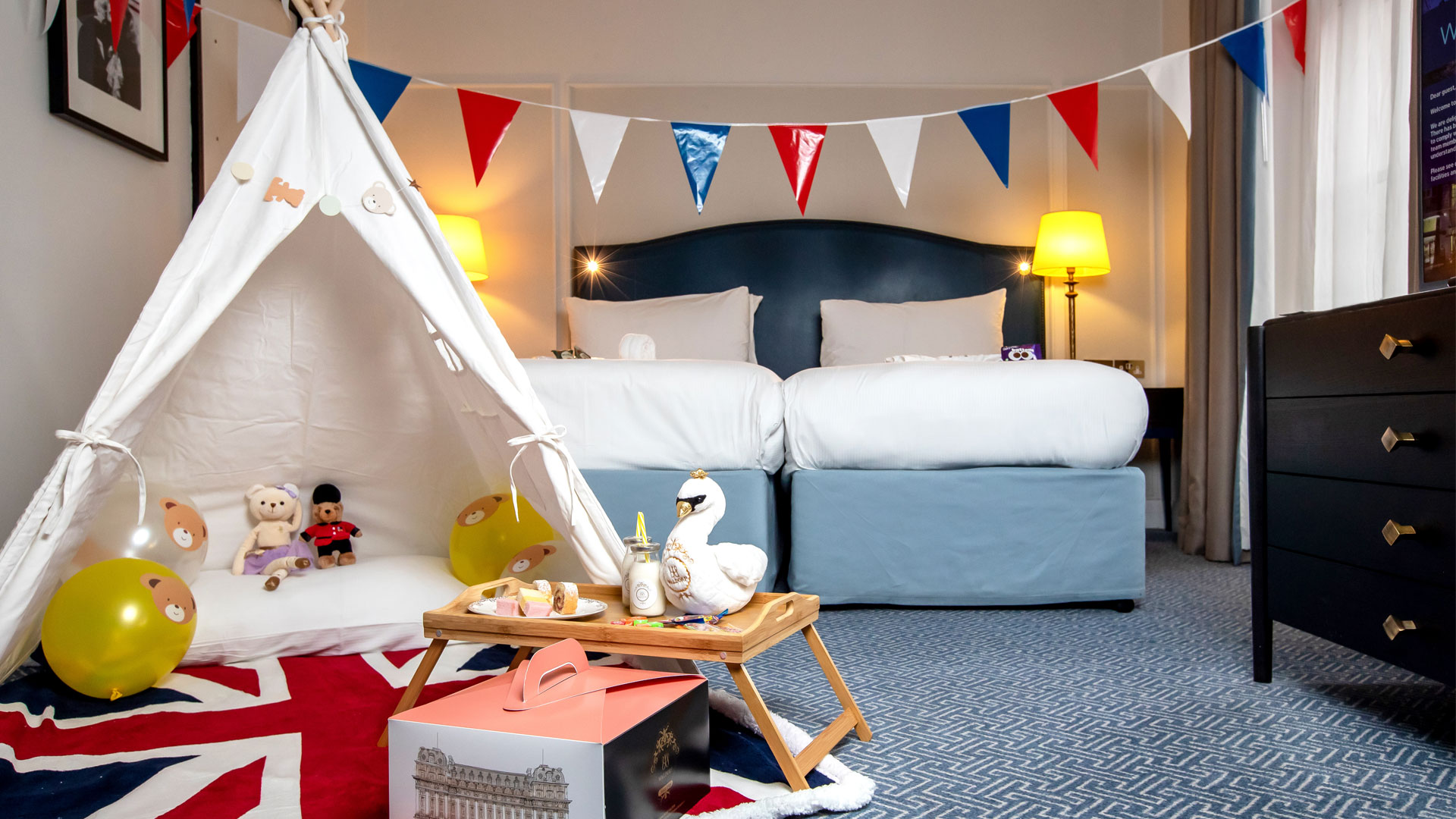 Wachen Sie im Waldorf Hilton London mit Londons Top-Attraktionen vor der Haustür auf. Bild mit Genehmigung von Hilton. Zweibett-Familienzimmer im Waldorf Hilton London mit Tipi, Fähnchen und Details zum Thema London.