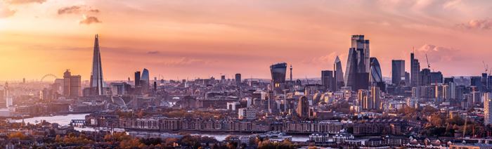 Panoramic view of London skyline at sunset, featuring The Shard, London Eye and City of London skyscrapers.
