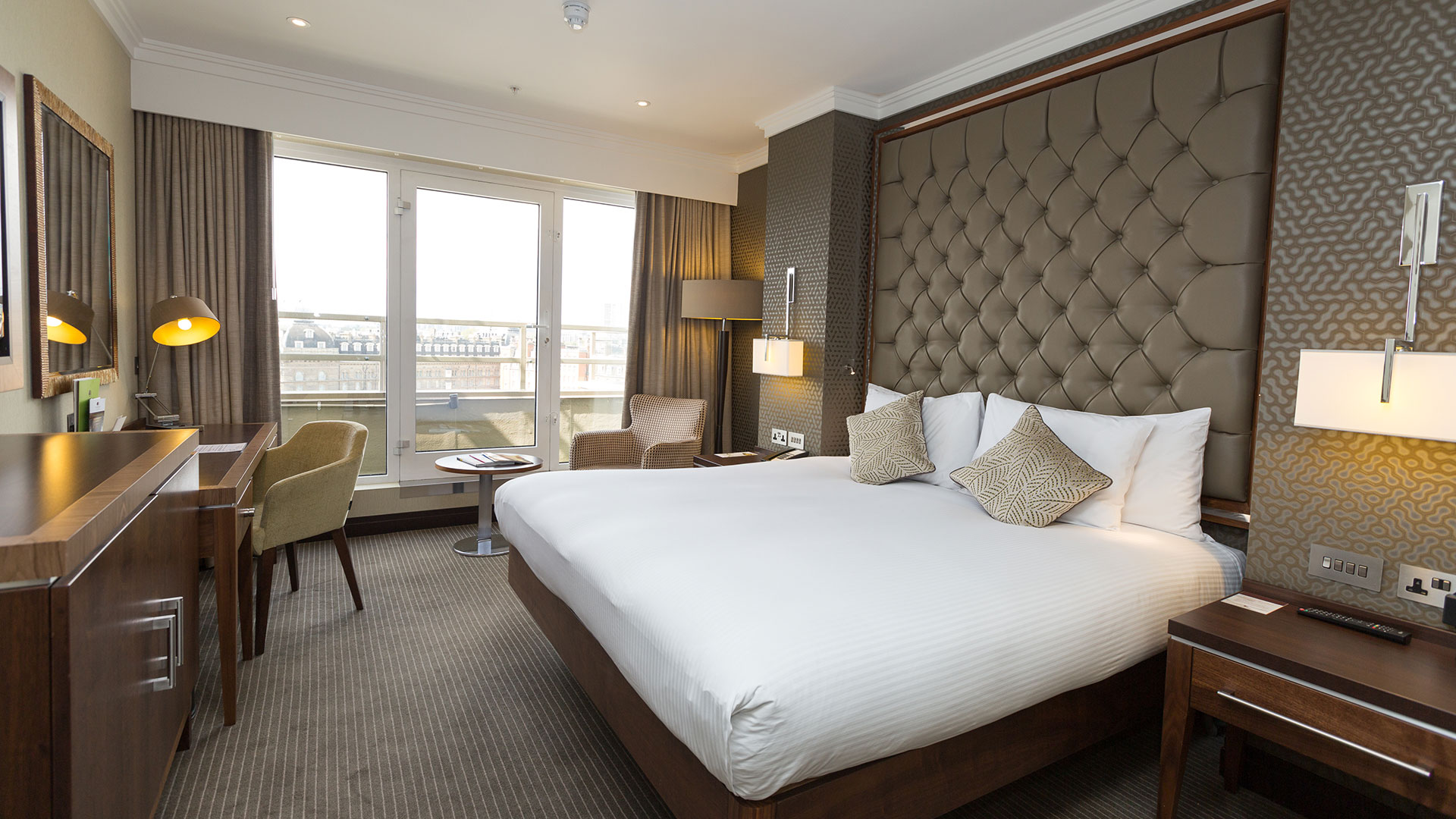 A big double bed in a spacious room with windows overlooking London
