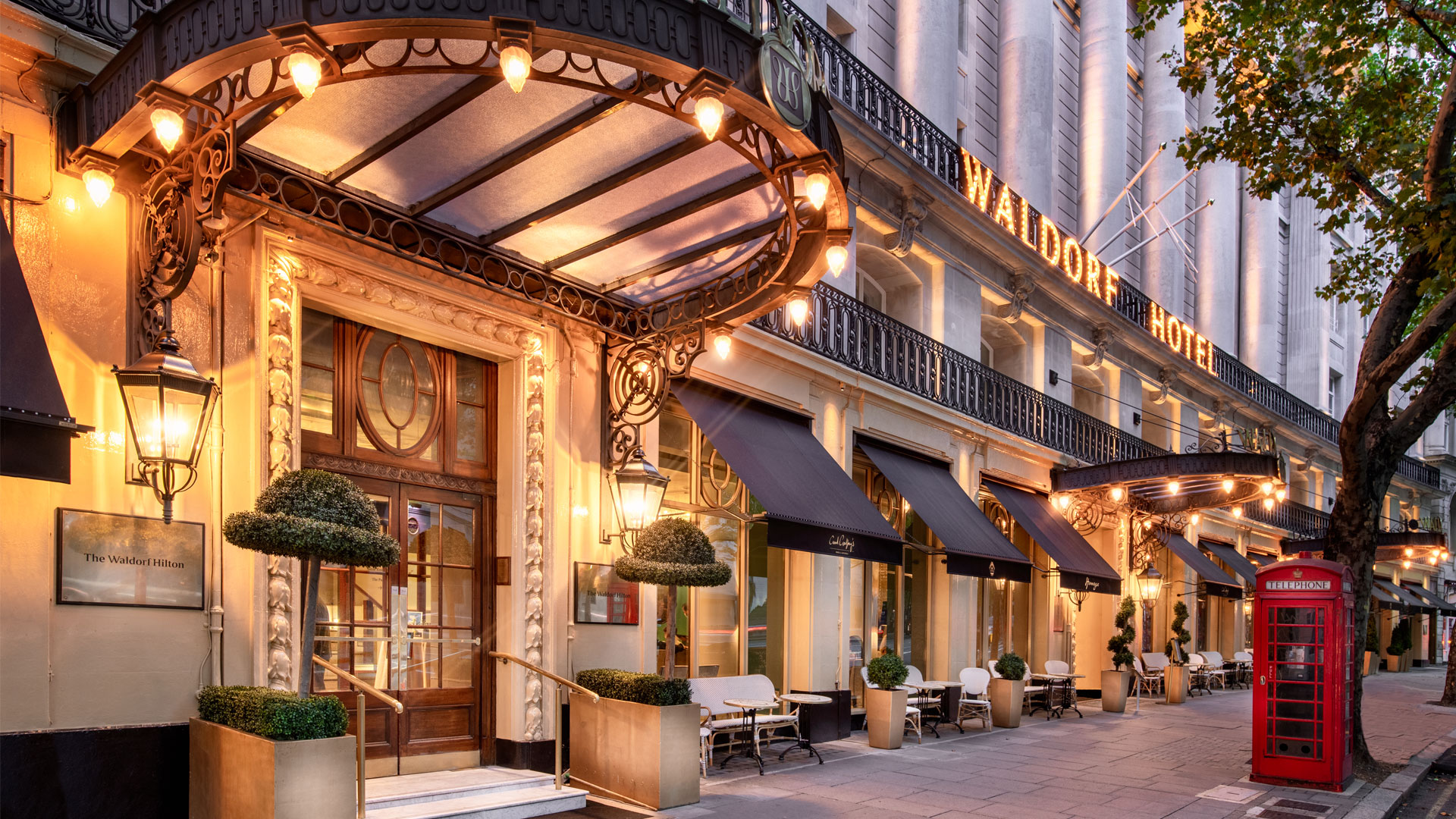 Extérieur du Waldorf Hilton de Londres illuminé en soirée.