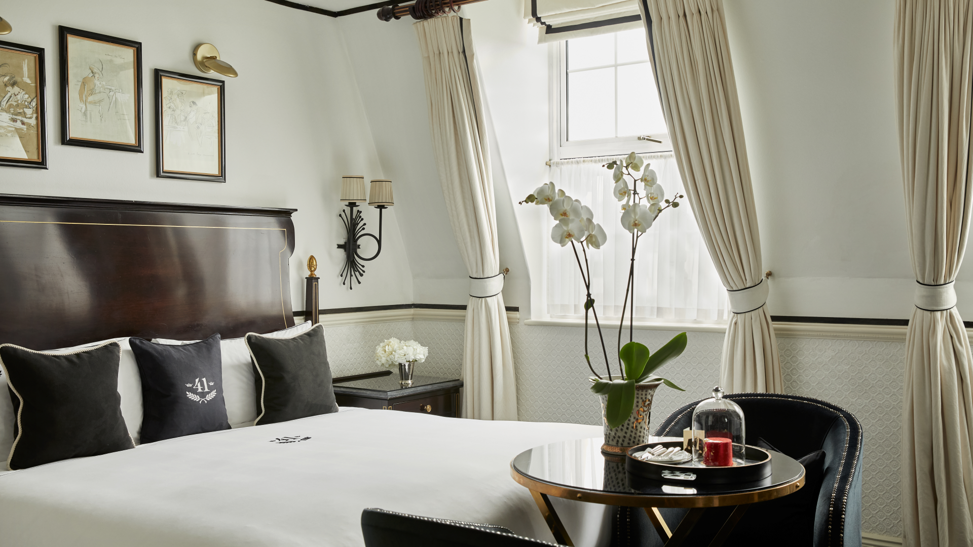 Executive king room at Hotel 41 featuring a rich mahogany king-sized bed with a table an two armchairs and framed art filling the walls