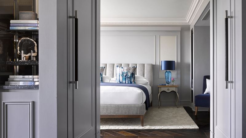 Choose from elegant rooms and suites for a luxury stay in one of the most sought-after London locations. Credit: InterContinental London Park Lane. Image courtesy of InterContinental London Park Lane. View of a luxury hotel room bed with white linens and blue cushion, with a bedside table and blue bedside lamp.