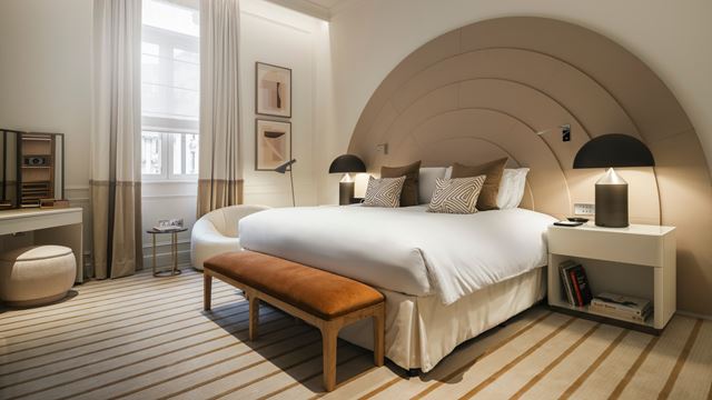 The Opera Suite at Sofitel London St James, featuring a contemporary-style alcove above the bed, striped carpets and cream furnishings.