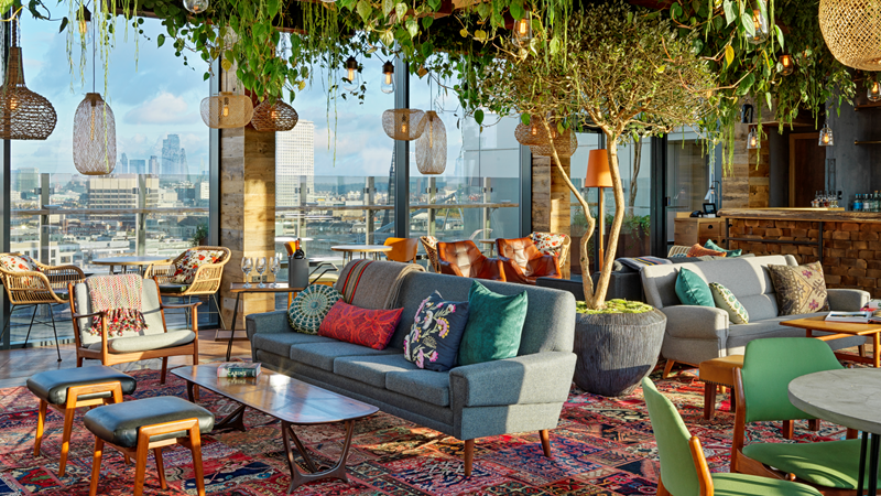 Spot the city's landmarks from the green haven of Treehouse Hotel London. Credit: Treehouse London. Image courtesy of Treehouse London. Trailing plants hang from the ceiling of the Nest lounge at Treehouse London with red Persian rugs, wooden hanging pendant lights and comfy chairs and sofas with floor-to-ceiling windows boasting a view of London's cityscape