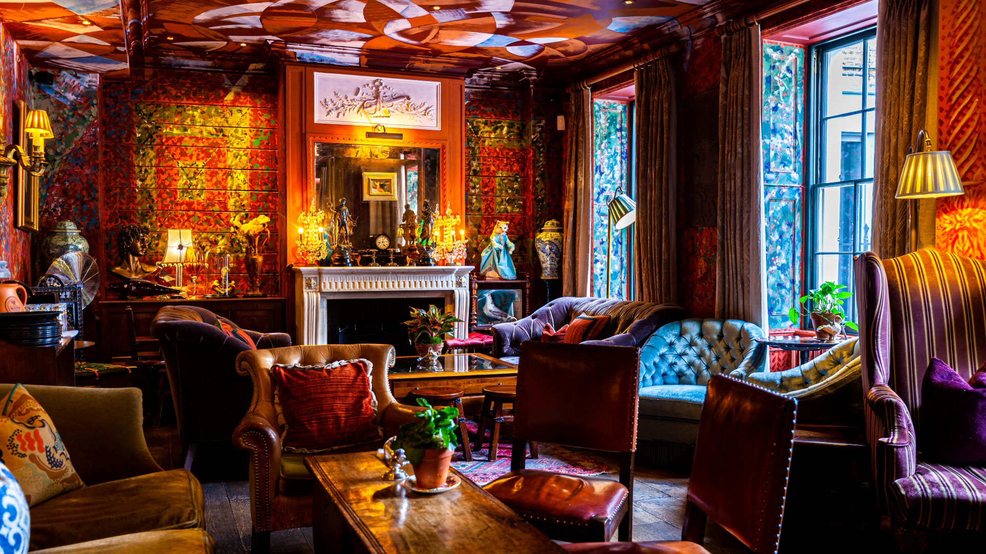 Communal area at Zetter Townhouse Clerkenwell with red patterned wallpaper, velvet sofas and wooden tables