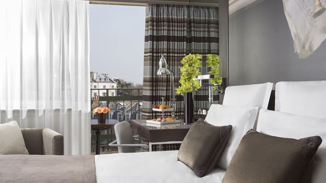 A room at The Lowndes London with a view across the local area from a large window, grey walls and a window seat.